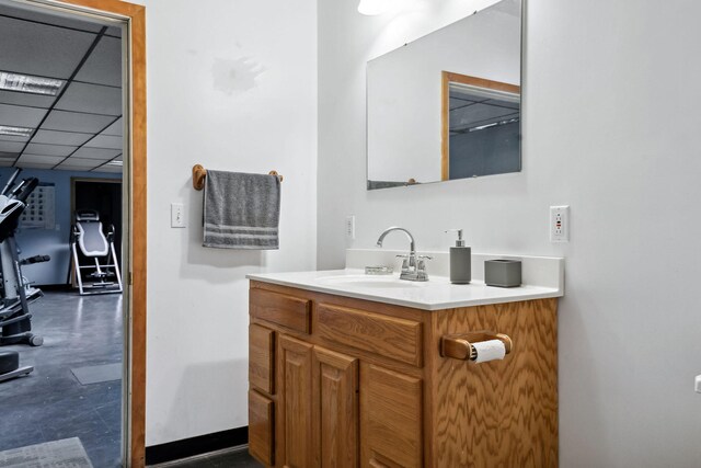 bathroom with a drop ceiling, vanity, and concrete flooring