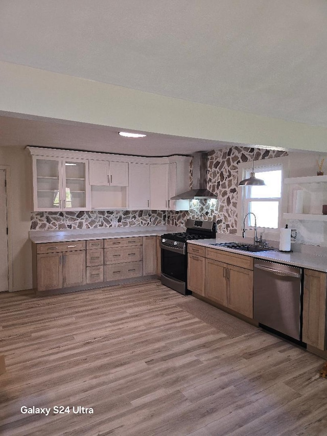 kitchen with wall chimney range hood, light hardwood / wood-style floors, black range, sink, and stainless steel dishwasher