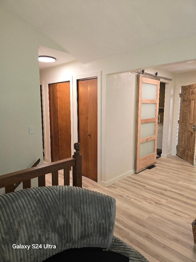 bedroom with light wood-type flooring and a barn door