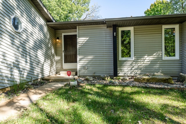 view of exterior entry featuring a lawn