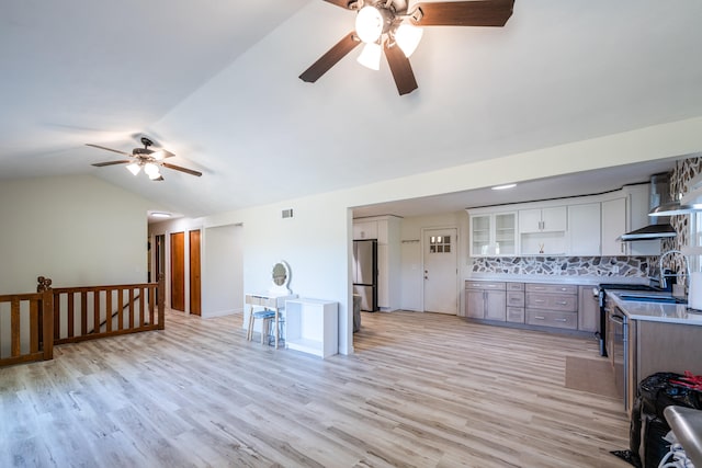 kitchen with white cabinets, backsplash, stainless steel refrigerator, light wood-type flooring, and vaulted ceiling