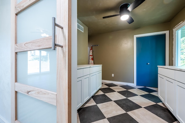 interior space with ceiling fan and white cabinets