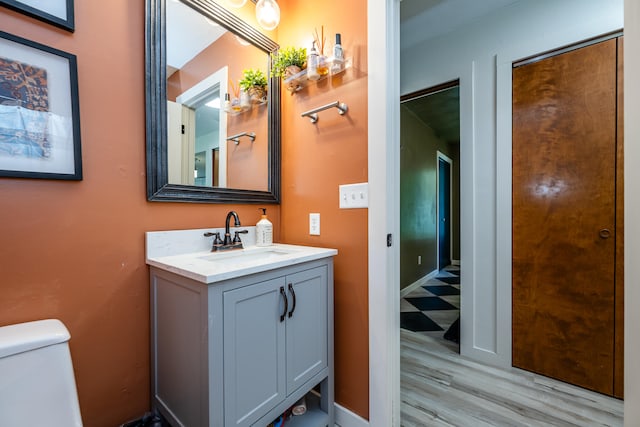 bathroom with toilet, vanity, and wood-type flooring