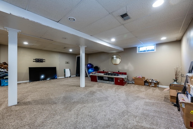 basement with a paneled ceiling and carpet