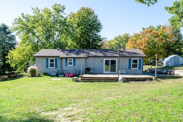 rear view of property with a storage unit, a yard, and a wooden deck