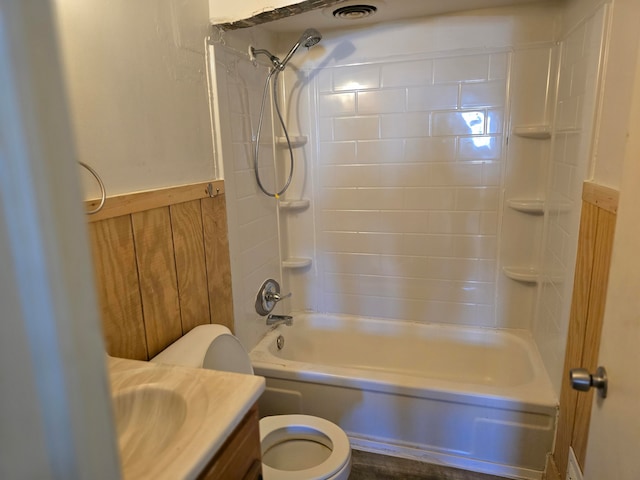 full bathroom featuring vanity, wooden walls, tiled shower / bath combo, and toilet