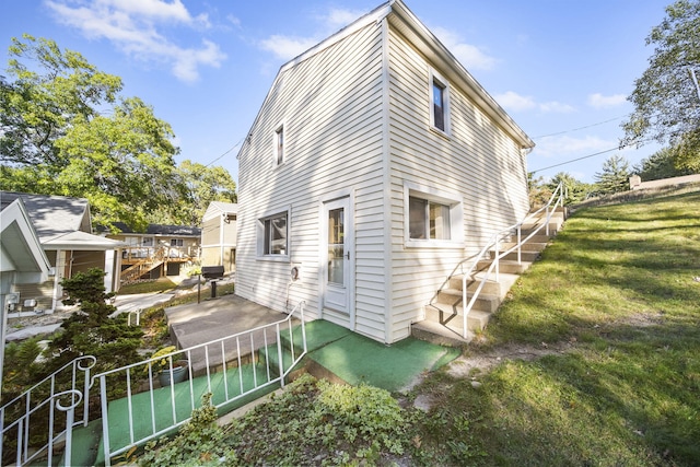 view of side of home with a patio area and a lawn