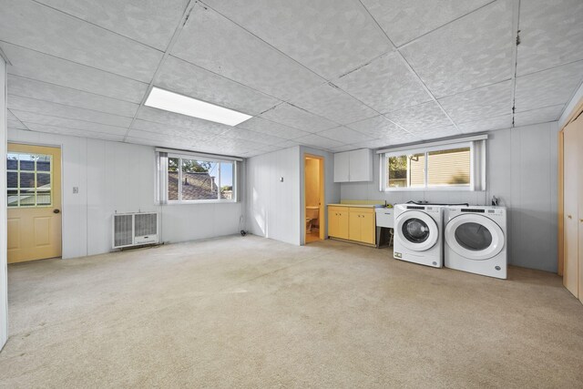 laundry room featuring heating unit, light colored carpet, washer and dryer, and cabinets