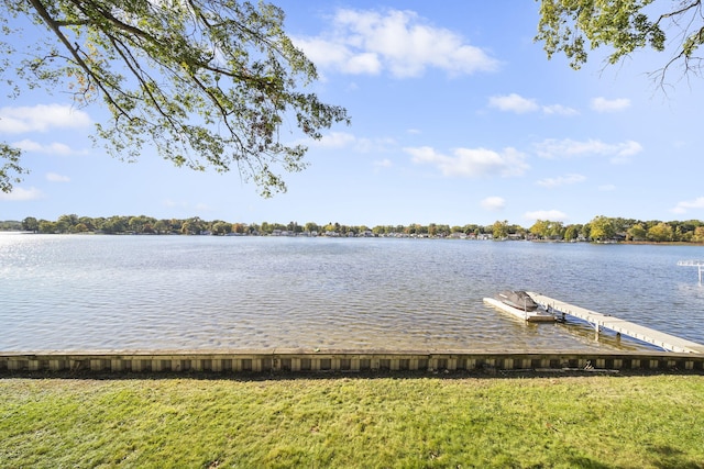 view of dock with a lawn and a water view