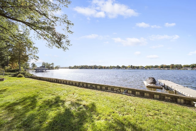 view of dock with a yard and a water view