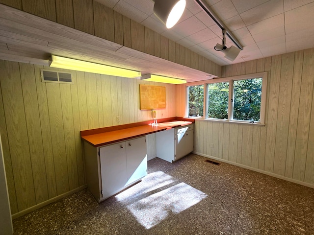 kitchen with wood walls and white cabinetry