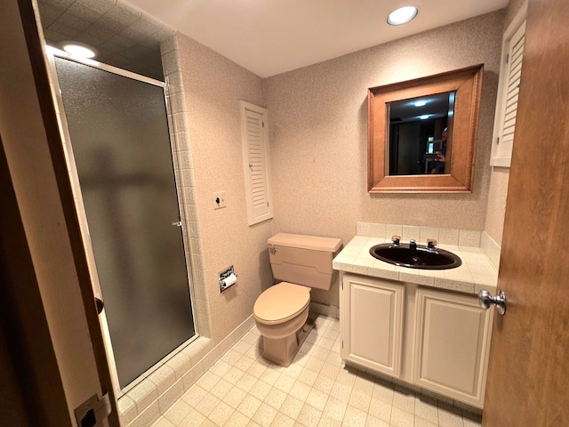 bathroom featuring a shower with door, vanity, and toilet