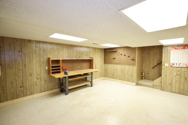 basement featuring a paneled ceiling and wood walls