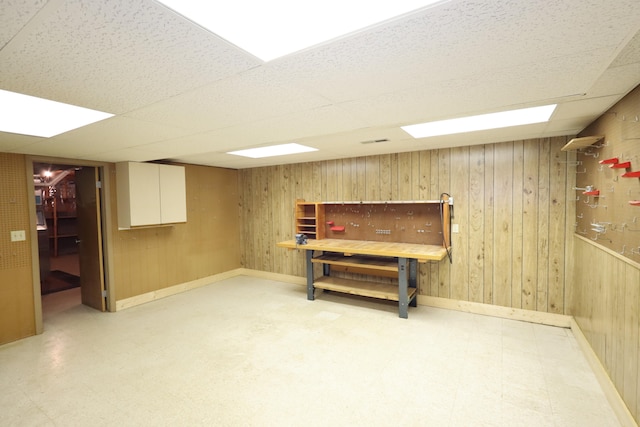 basement with a paneled ceiling and wooden walls