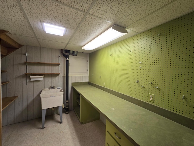 unfurnished office featuring wooden walls and a drop ceiling