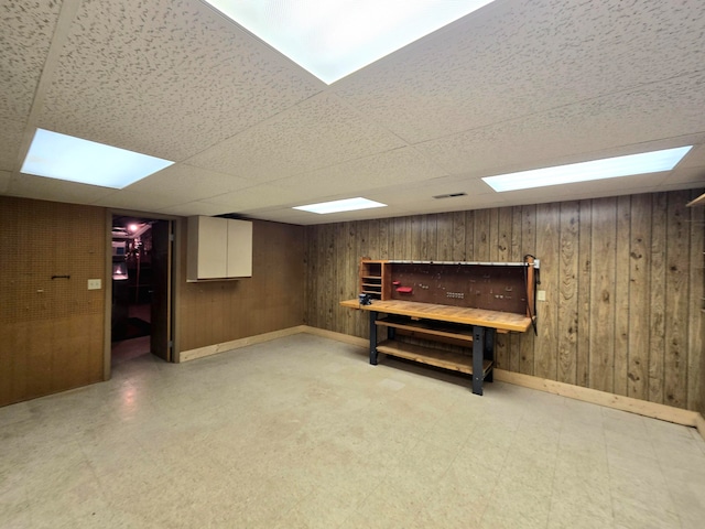 basement with a paneled ceiling and wooden walls