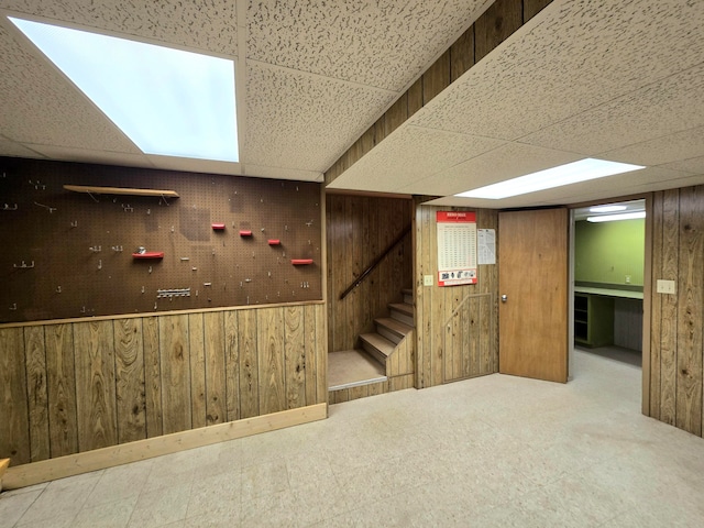 basement with a drop ceiling and wood walls