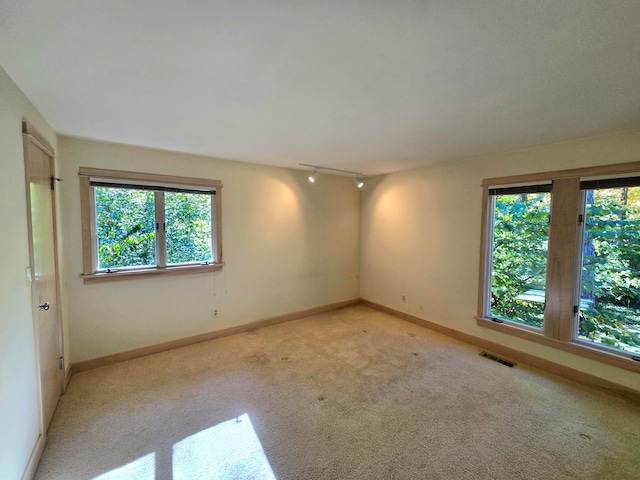 unfurnished room featuring light carpet and rail lighting