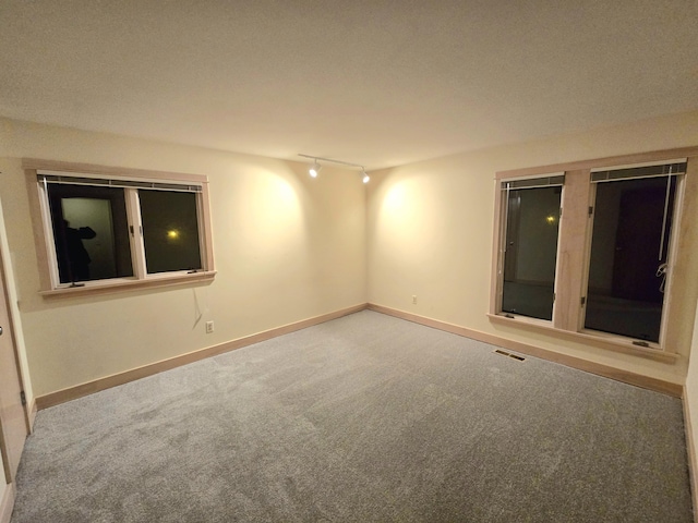 carpeted empty room featuring a textured ceiling and rail lighting