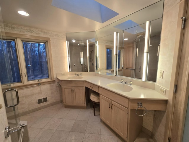 bathroom featuring tile patterned flooring, vanity, an enclosed shower, and tile walls