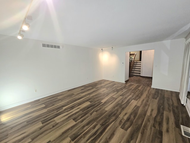 spare room with dark hardwood / wood-style flooring and rail lighting