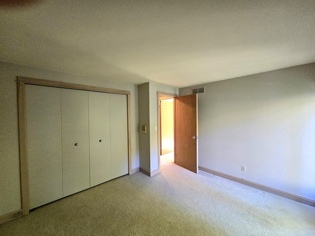 unfurnished bedroom featuring light carpet, a textured ceiling, and a closet