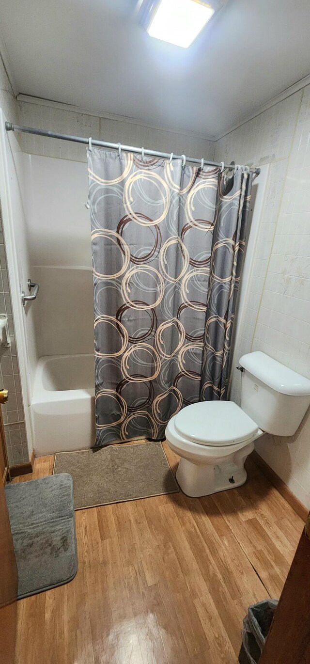 bathroom with toilet, wood-type flooring, and shower / bath combo