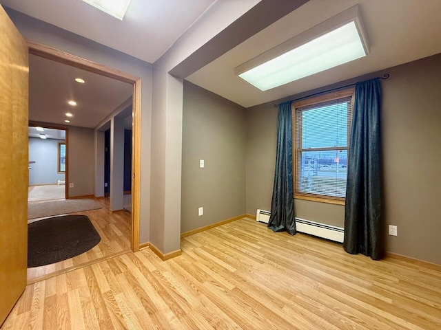 unfurnished room with light hardwood / wood-style flooring and a baseboard heating unit