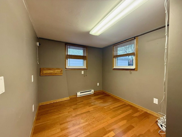 spare room featuring baseboard heating and light hardwood / wood-style flooring