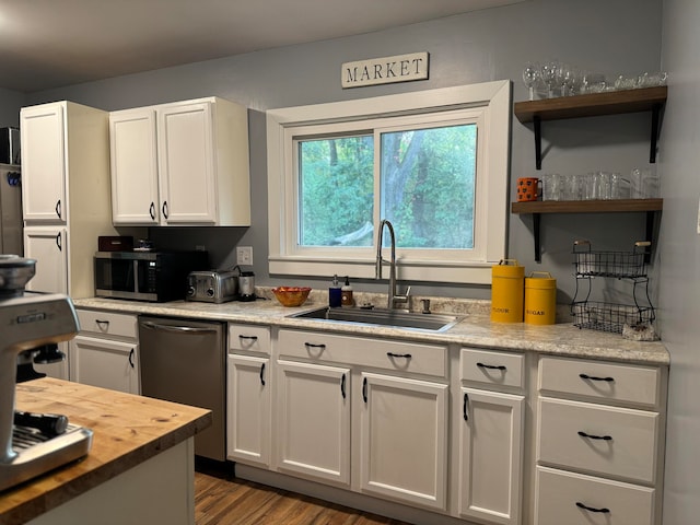 kitchen with stainless steel appliances, sink, wood-type flooring, and white cabinets