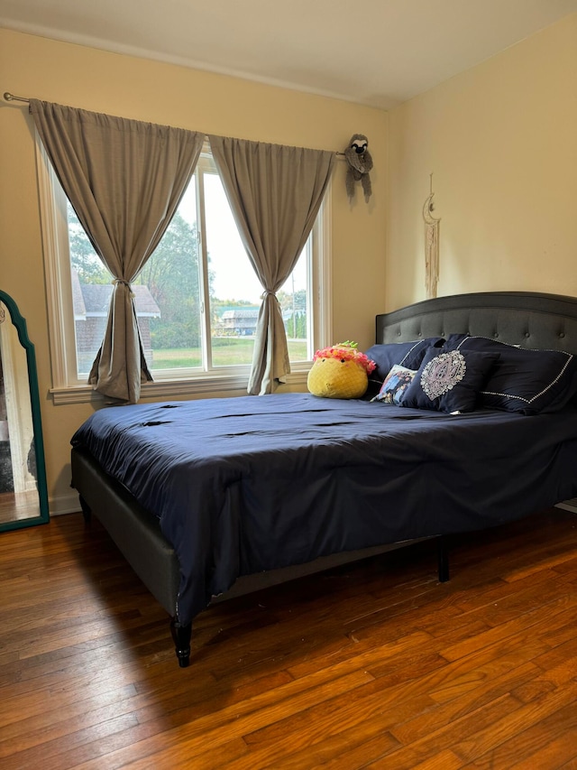 bedroom with multiple windows and dark hardwood / wood-style flooring