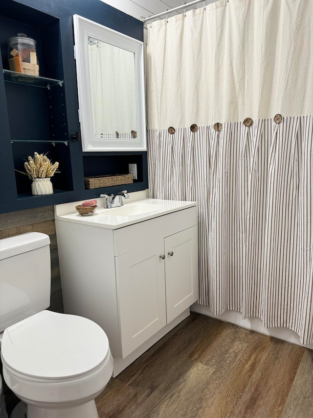 bathroom with a shower with shower curtain, hardwood / wood-style flooring, vanity, and toilet