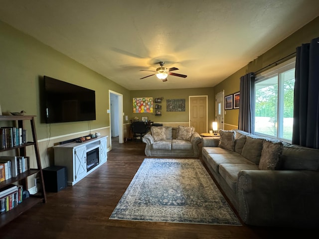 living room featuring a fireplace, ceiling fan, and dark wood-type flooring