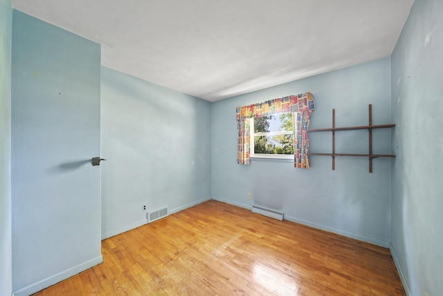 spare room with light wood-type flooring and a baseboard radiator