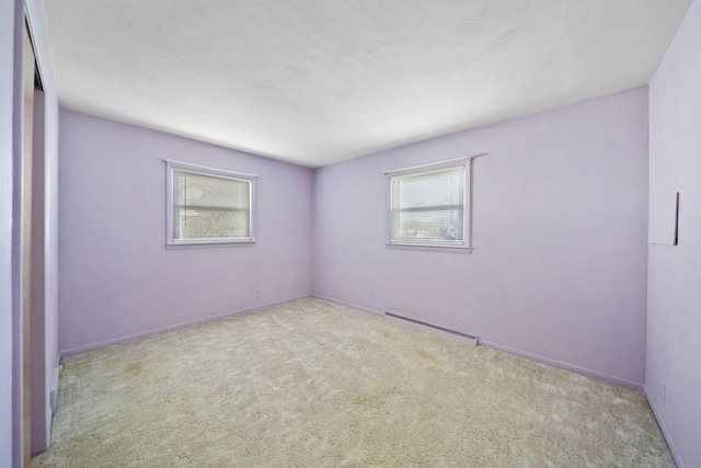 spare room with light carpet, a wealth of natural light, and a baseboard radiator