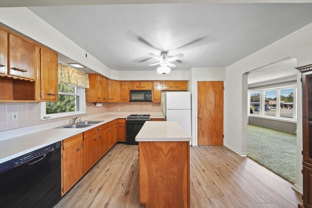 kitchen featuring black appliances, light hardwood / wood-style flooring, a center island, and a healthy amount of sunlight