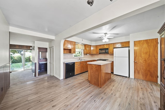 kitchen featuring sink, tasteful backsplash, a kitchen island, light hardwood / wood-style flooring, and black appliances