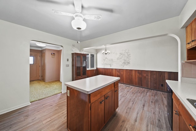 kitchen featuring a kitchen island, wooden walls, hanging light fixtures, and light hardwood / wood-style flooring