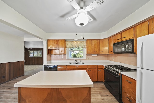 kitchen featuring black appliances, a center island, sink, and light hardwood / wood-style flooring