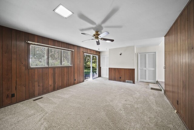 unfurnished living room featuring wood walls and light colored carpet