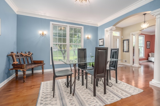 dining space featuring wood-type flooring, decorative columns, and ornamental molding