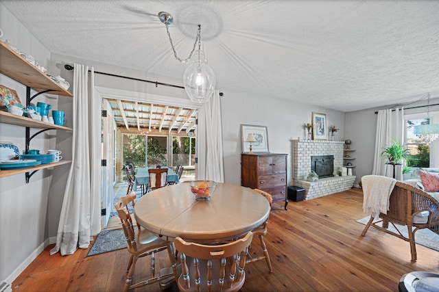 dining room featuring a brick fireplace, a wealth of natural light, and hardwood / wood-style floors