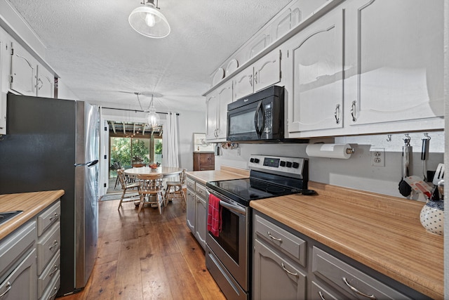 kitchen with a textured ceiling, appliances with stainless steel finishes, hanging light fixtures, dark hardwood / wood-style floors, and gray cabinets