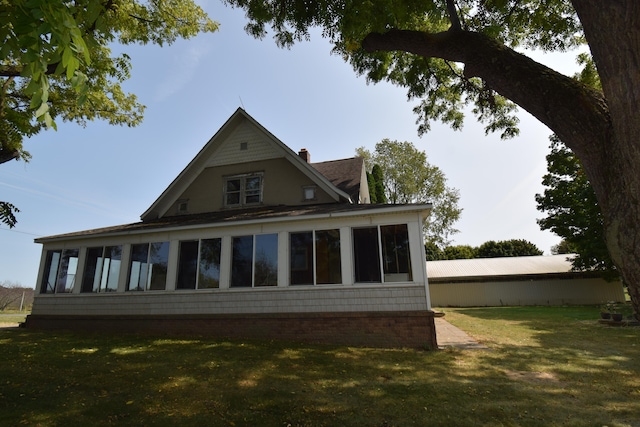 view of side of home featuring a sunroom and a lawn