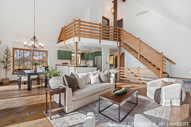 living room with an inviting chandelier, wood-type flooring, and high vaulted ceiling