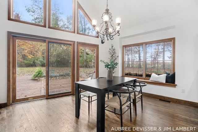 dining space featuring a towering ceiling, wood-type flooring, and a chandelier