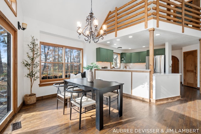 dining space featuring dark wood-type flooring, a wealth of natural light, and a chandelier