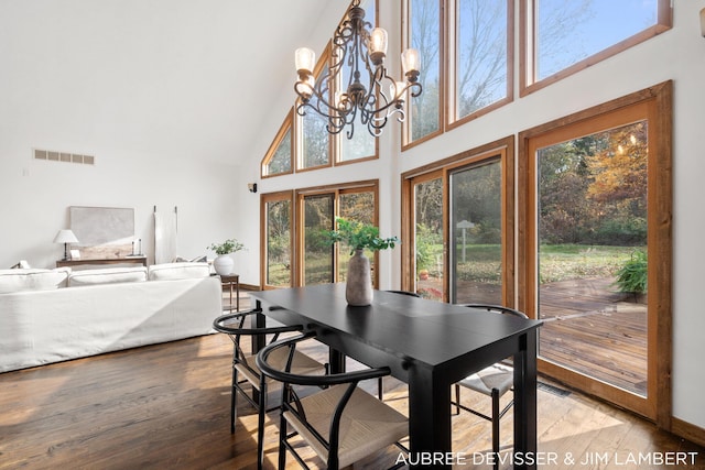 dining space with a high ceiling, a notable chandelier, and hardwood / wood-style flooring