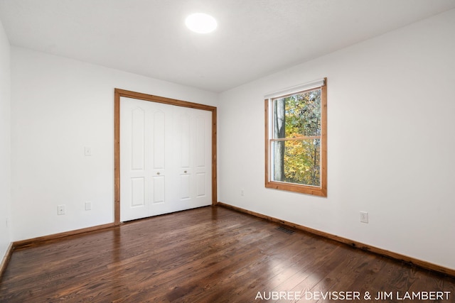 unfurnished bedroom with dark wood-type flooring and a closet