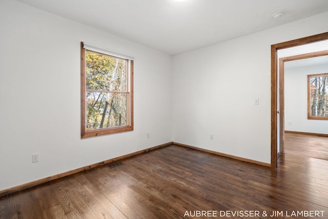 unfurnished room featuring a healthy amount of sunlight and dark hardwood / wood-style floors